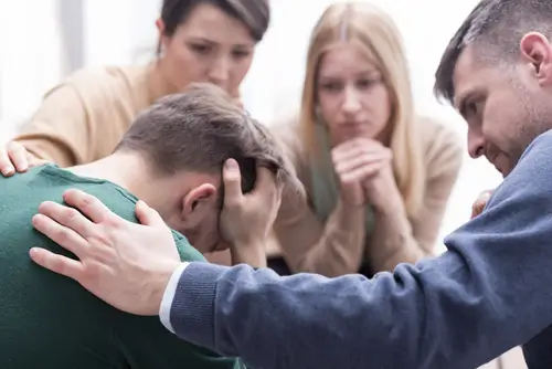 group of people comforting man