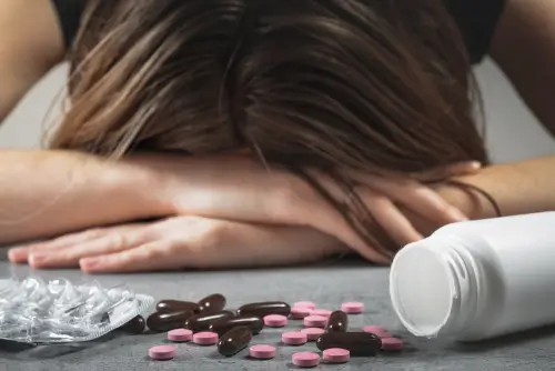 woman putting her head down with pills in front of her