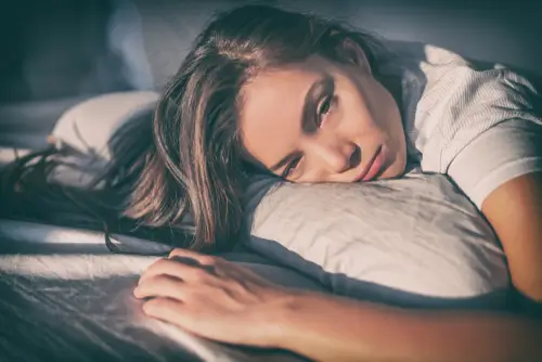 why does depression make you tired? woman laying head on pillow