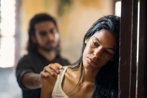 woman looking sad because of her trauma bond addiction with the man behind her